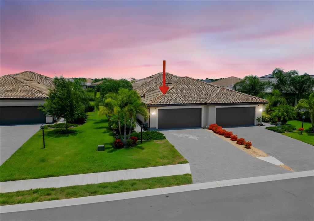 An exterior view of a residential home with a tiled roof and two garage doors — 5323 WHITE SAND COVE, BRADENTON, FL