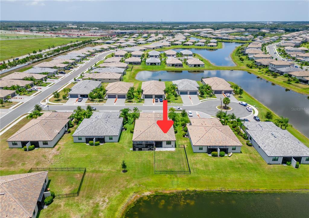 An aerial view shows a residential neighborhood with houses, lawns, and a central pond — 5323 WHITE SAND COVE, BRADENTON, FL