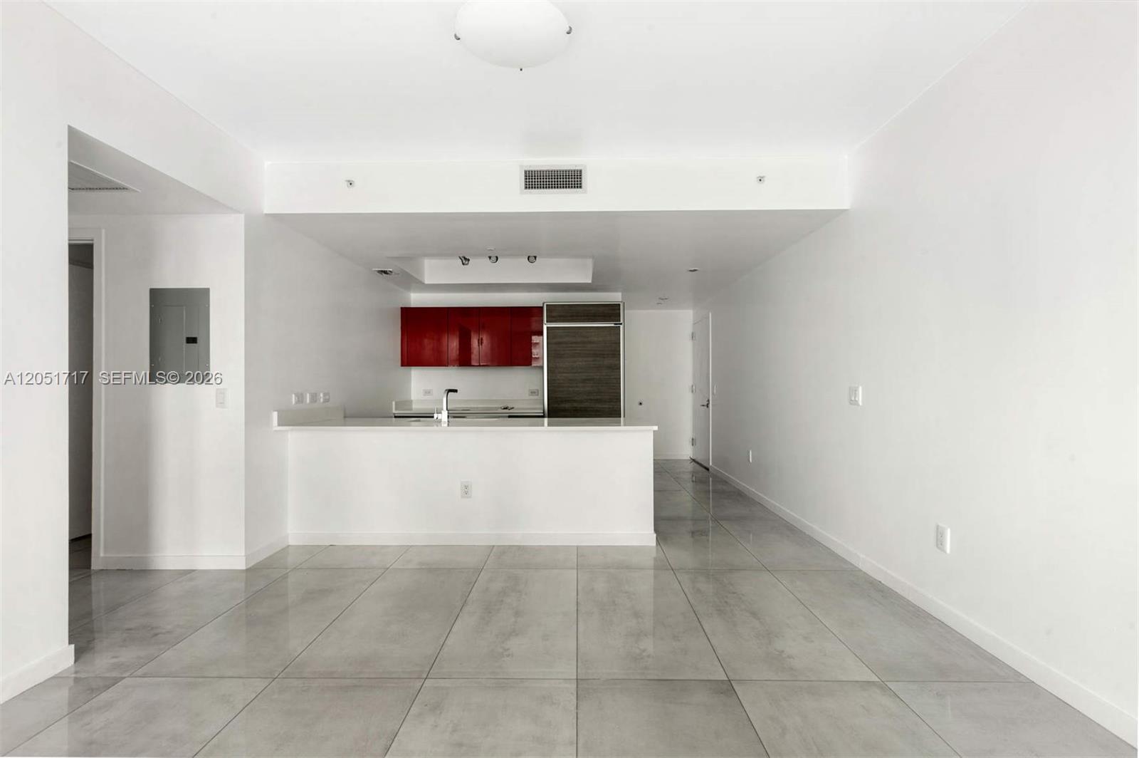 An open-concept kitchen features red cabinets, stainless steel appliances, and large gray floor tiles — 1100 S Miami Ave # 1504, Miami FL 33130, MIAMI, FL