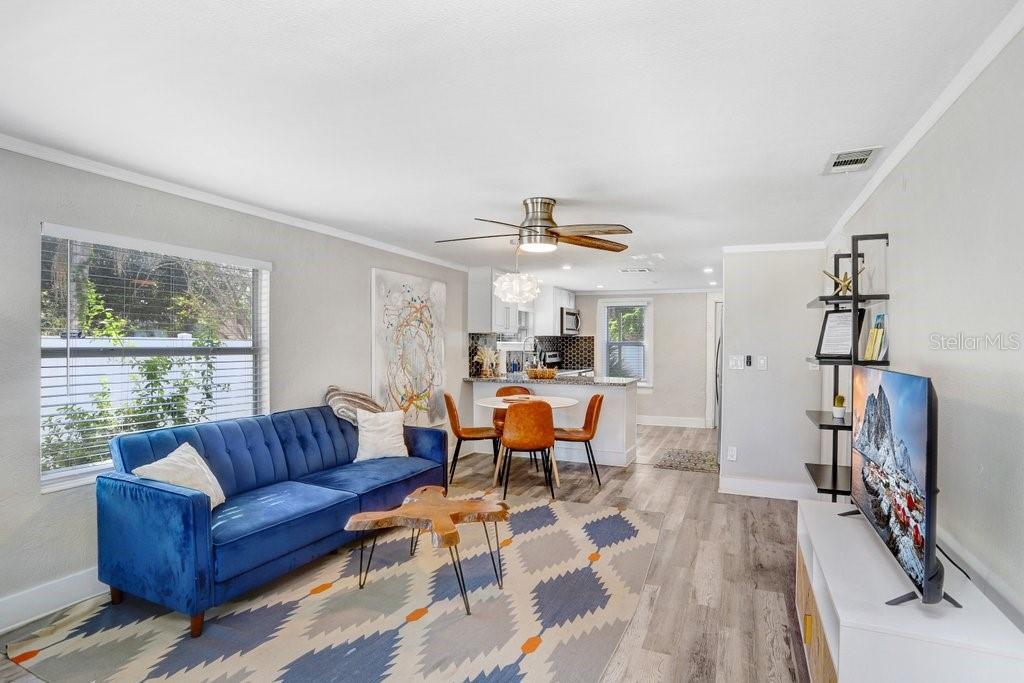 A living room with a blue sofa, patterned rug, and an open kitchen in back — 1811 E PALIFOX STREET, TAMPA, FL
