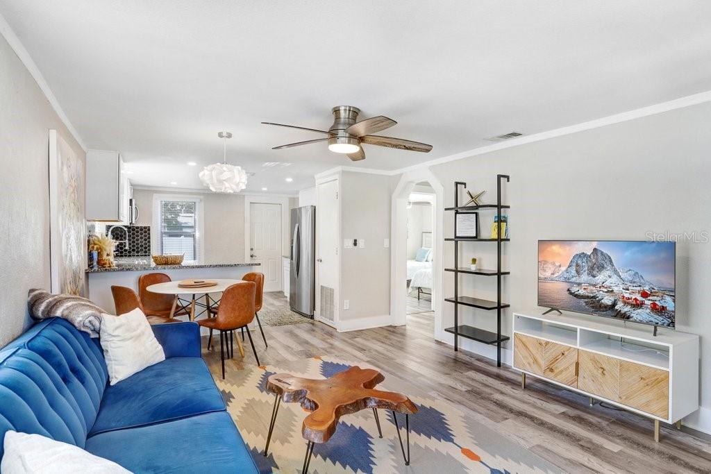 A living room with a blue sofa, wood coffee table, and open kitchen with dining area — 1811 E PALIFOX STREET, TAMPA, FL