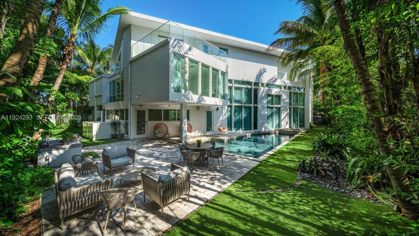 A modern two-story house features a patio, swimming pool, and lush surrounding trees — 480 Ocean Blvd, Golden Beach FL 33160, GOLDEN BEACH, FL