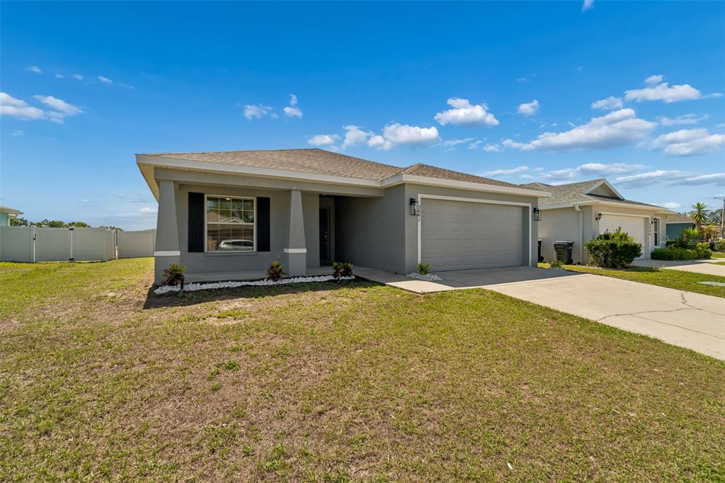 A gray single-story house with a two-car garage and a front porch under a blue sky — 3042 GRAND PRESERVE BOULEVARD, MULBERRY, FL