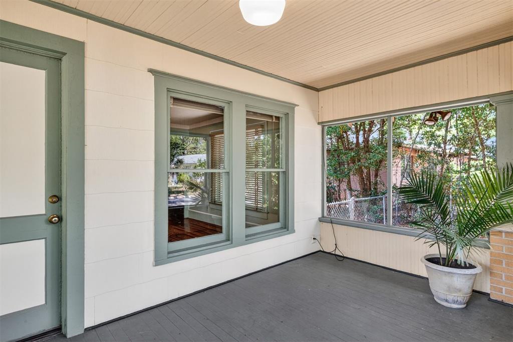 A covered porch features white walls, green trim, a gray floor, and a potted palm plant — 616 NE 7TH STREET, GAINESVILLE, FL