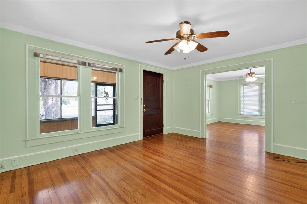 A living room with light green walls, hardwood floors, a ceiling fan, and a doorway — 616 NE 7TH STREET, GAINESVILLE, FL