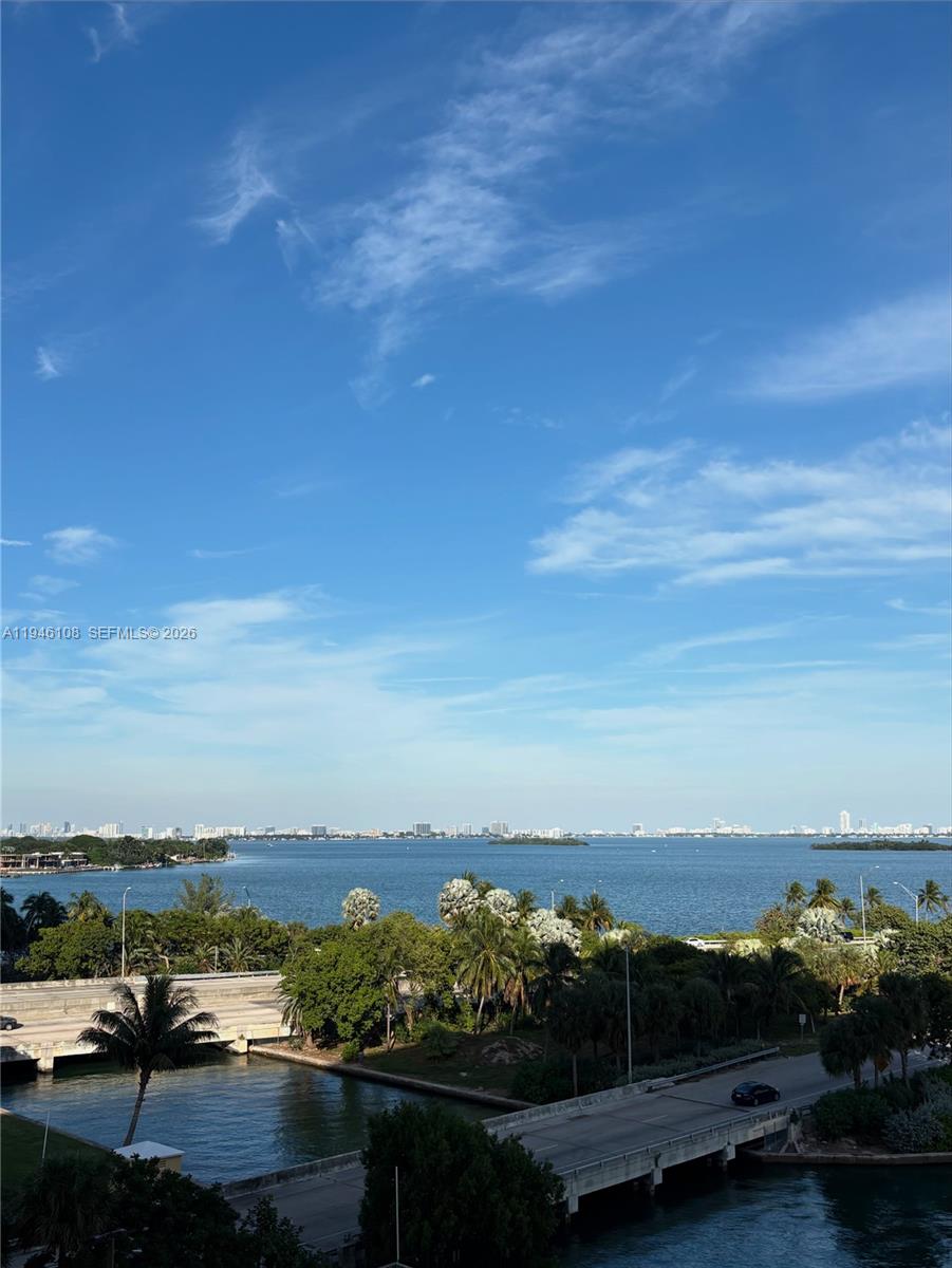 An elevated view of a bay with a bridge, lush trees, and a distant skyline — 600 NE 36th St # 714, Miami FL 33137, MIAMI, FL