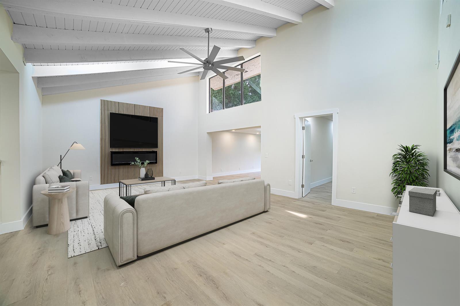 A living room with a vaulted ceiling, wood-slat fireplace wall, and light wood flooring — 8008 Eastlake Drive, Boca Raton FL 33433, BOCA RATON, FL