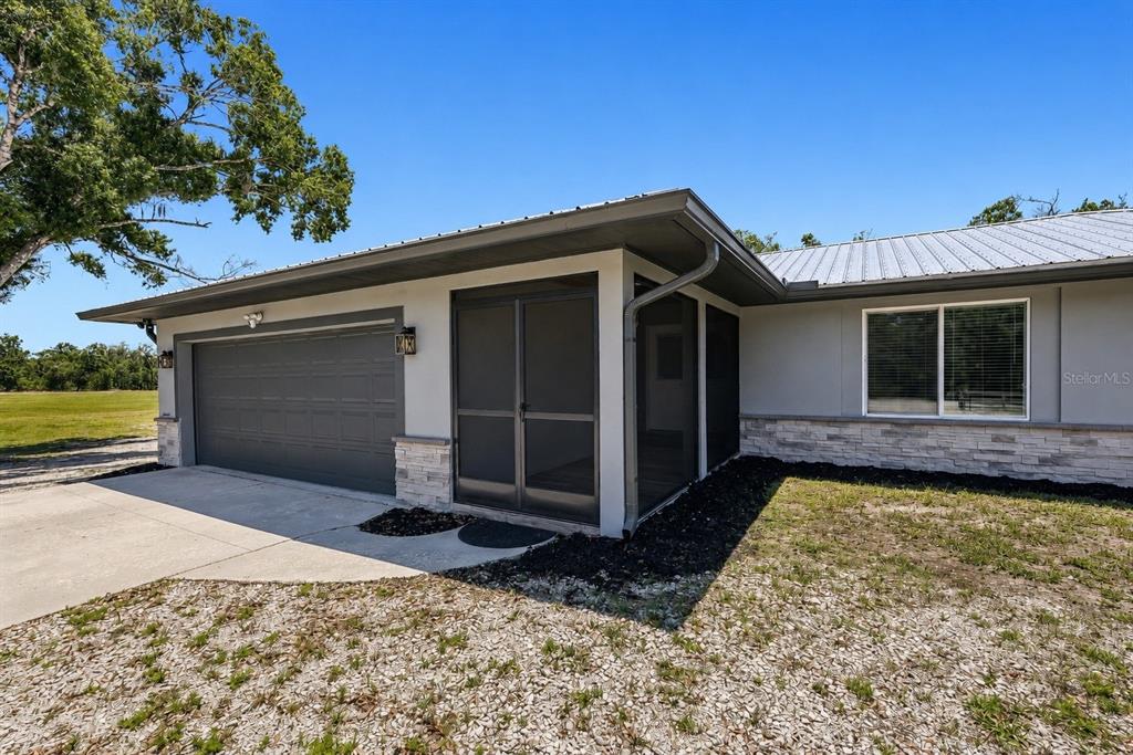 A gray house exterior features a two-car garage, a screened-in porch, and stone accents — 5361 MYAKKA VALLEY TRAIL, SARASOTA, FL