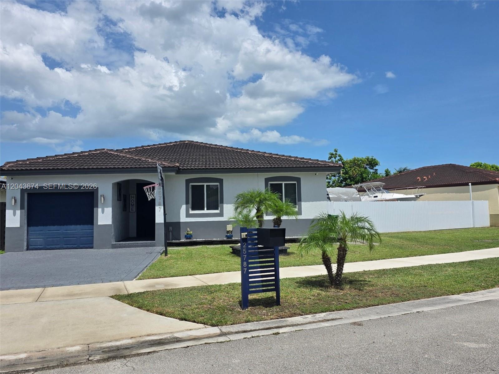 A single-story house with a blue garage door, dark roof, and a front yard mailbox — 25787 SW 127th Pl # 25787, Homestead FL 33032, HOMESTEAD, FL