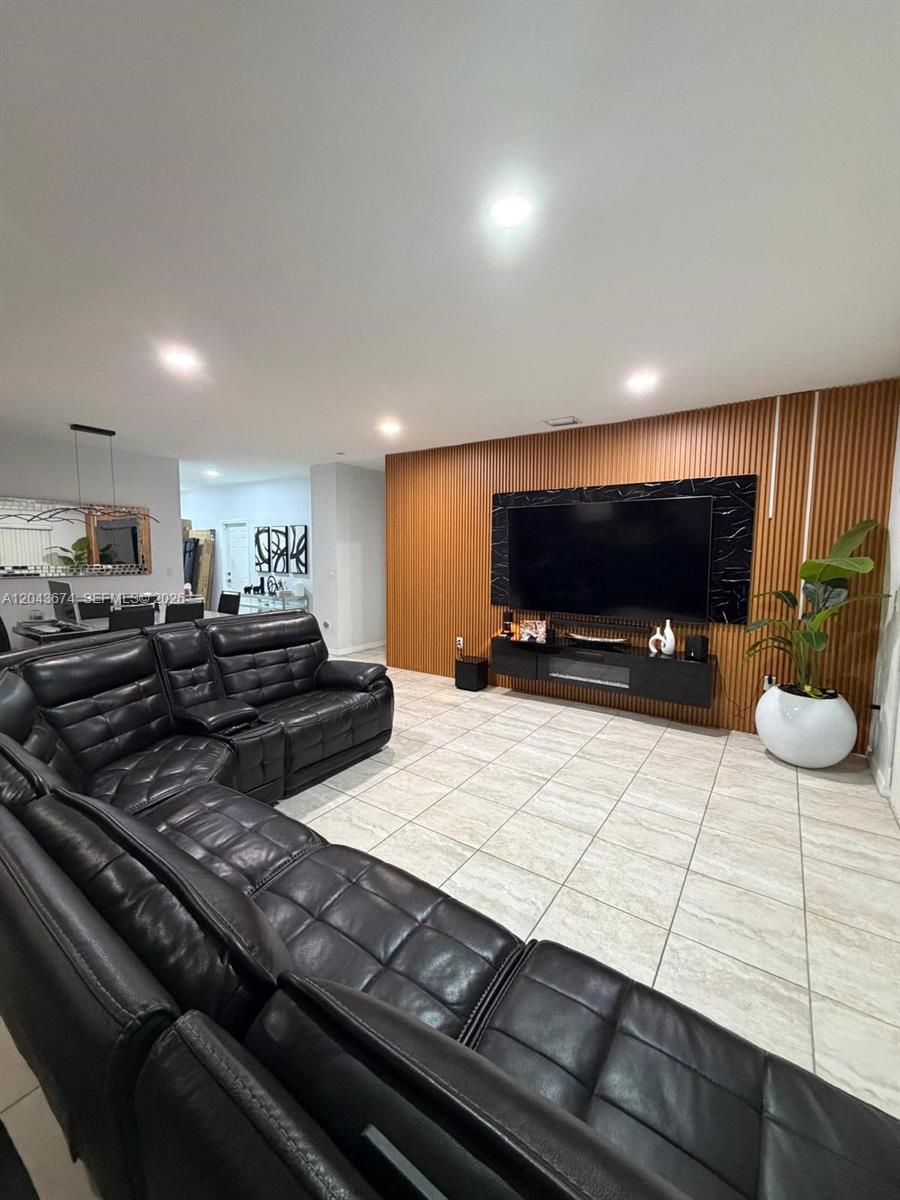 A living room features a black leather sectional, tiled floors, and a wood-slatted accent wall — 25787 SW 127th Pl # 25787, Homestead FL 33032, HOMESTEAD, FL