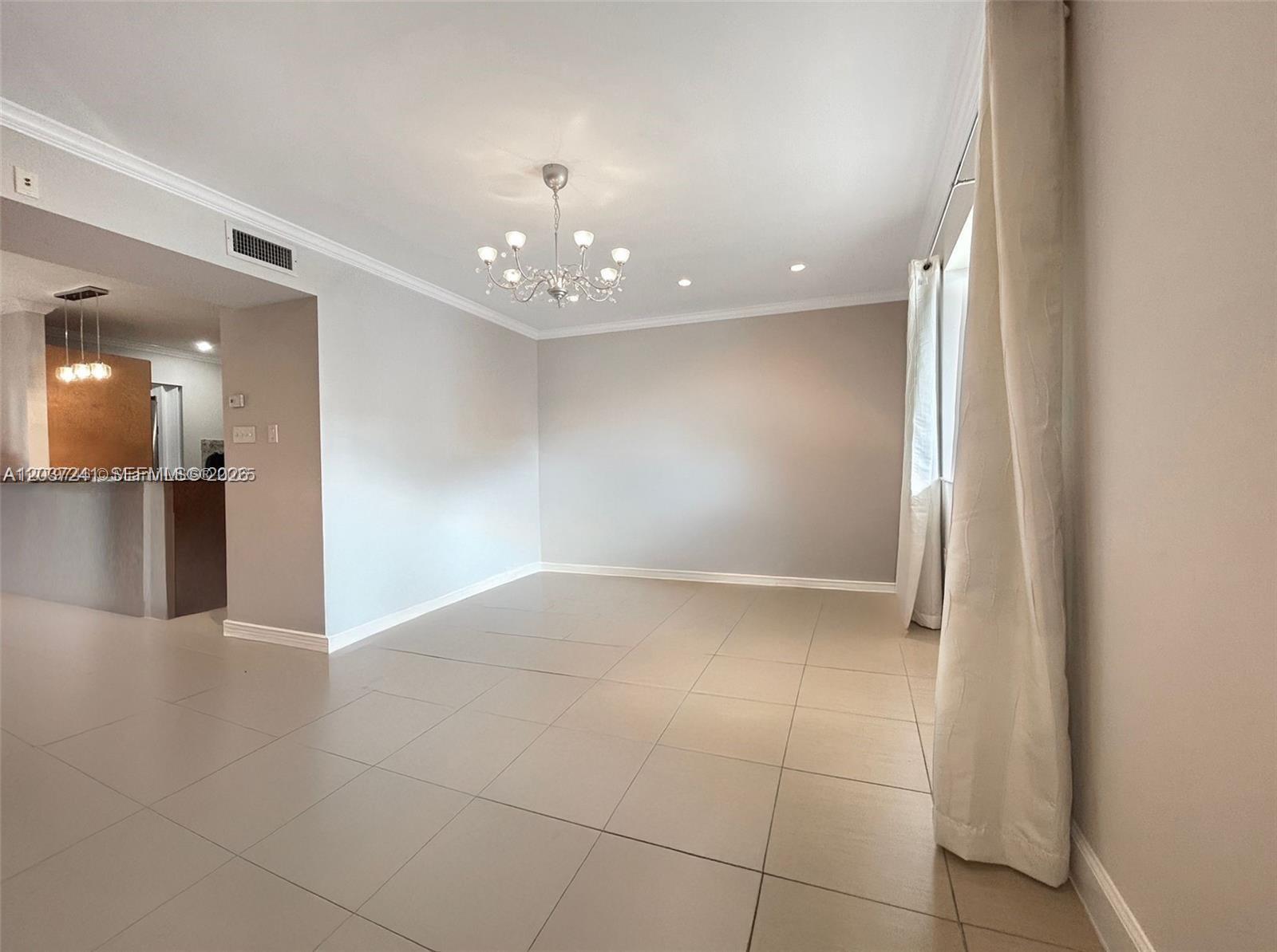 An empty dining room features large beige floor tiles, a chandelier, and white walls — 8401 SW 107th Ave # 176E, Miami FL 33173, MIAMI, FL