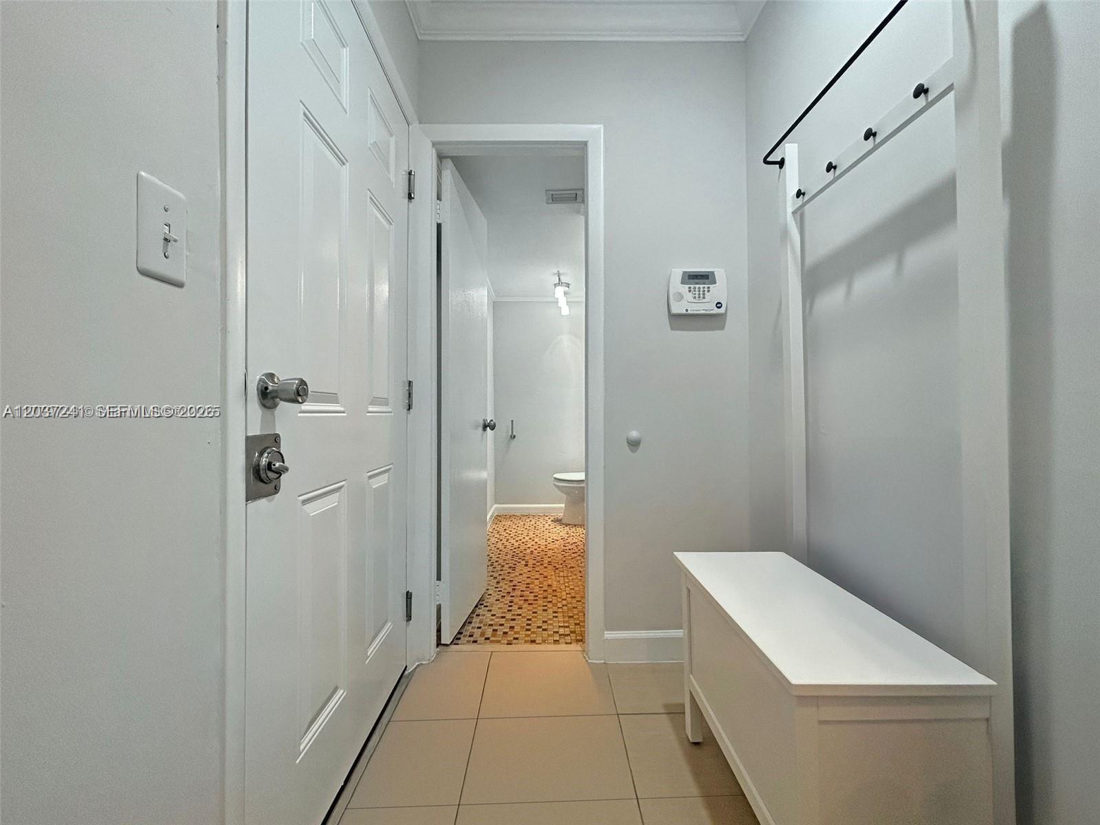 A hallway features a white bench, coat rack, and a doorway leading to a bathroom — 8401 SW 107th Ave # 176E, Miami FL 33173, MIAMI, FL