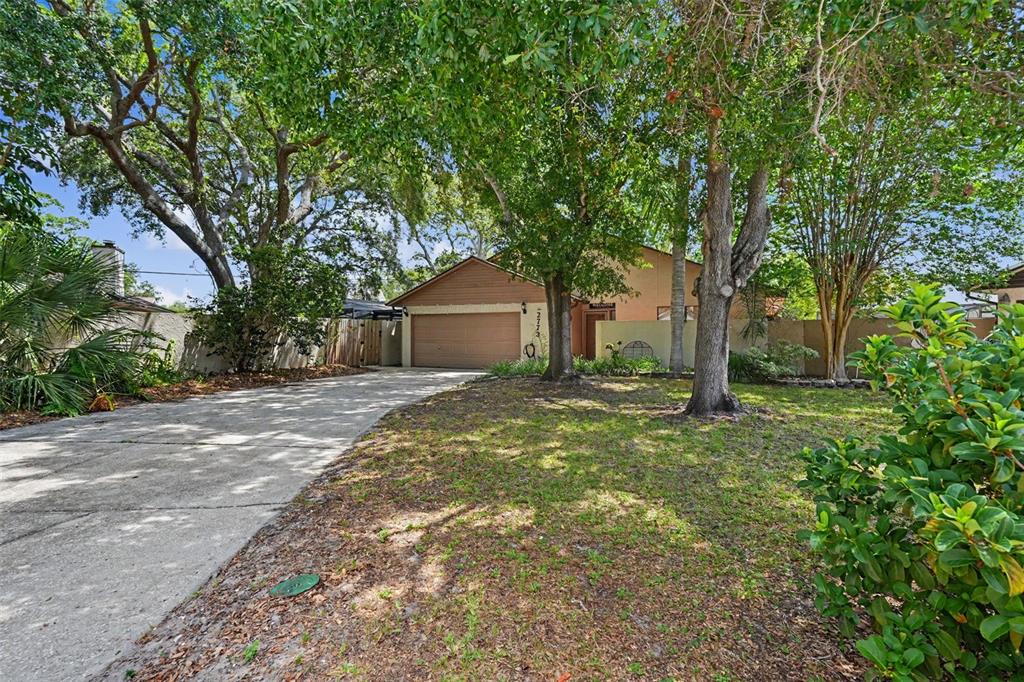 A single-story house with a brown garage and driveway sits behind large trees — 2773 JEFFREY DRIVE, PALM HARBOR, FL