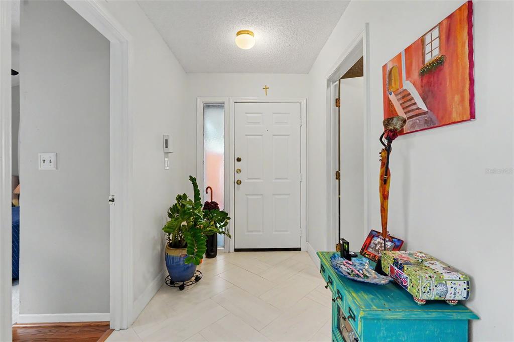 An entryway features white walls, a white front door, light tile flooring, and a console table — 2773 JEFFREY DRIVE, PALM HARBOR, FL