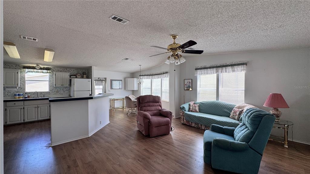 An open-concept living room and kitchen with wood-look flooring and a ceiling fan — 236 RAMSGATE WAY, HAINES CITY, FL