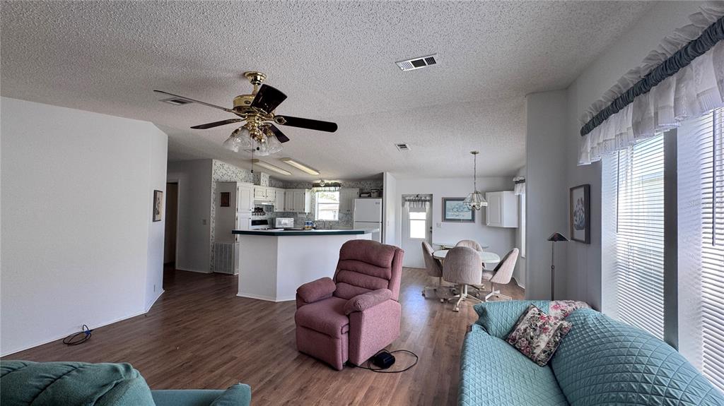 An open-concept living room and kitchen featuring wood-look flooring, a ceiling fan, and furniture — 236 RAMSGATE WAY, HAINES CITY, FL
