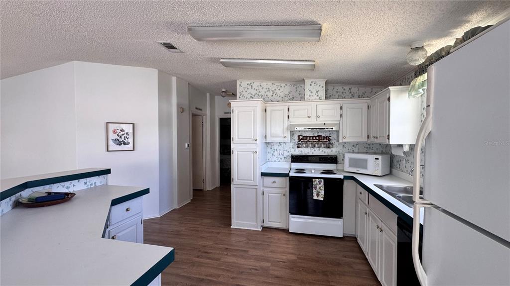 A kitchen features white cabinets, a black stove, a microwave, and a breakfast bar — 236 RAMSGATE WAY, HAINES CITY, FL