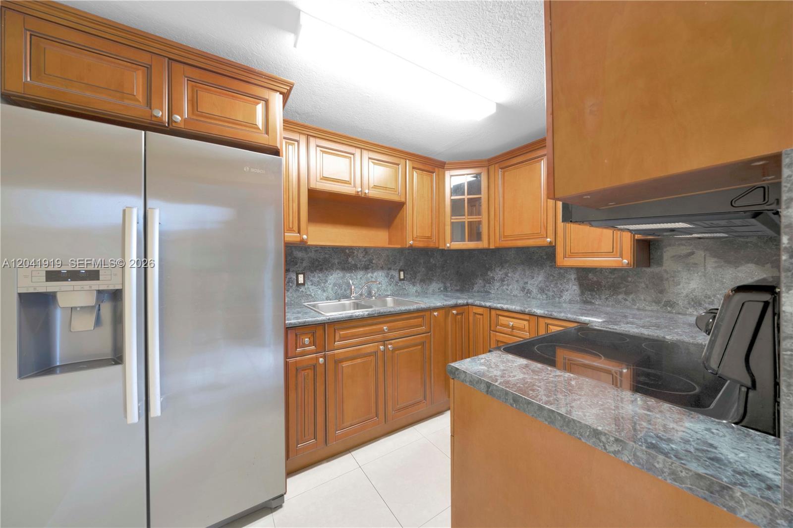 A kitchen features wood cabinets, stainless steel appliances, and gray stone-look countertops — 1701 NW 37th Ave # B, Miami FL 33125, MIAMI, FL
