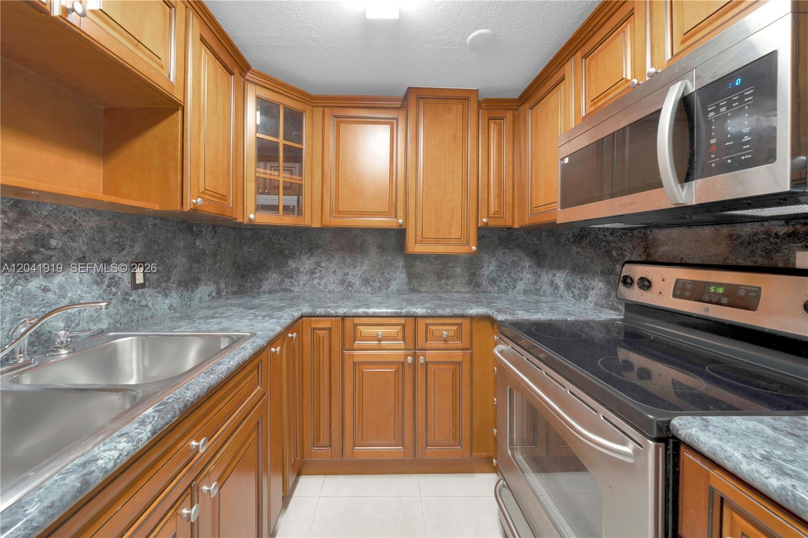 A kitchen features wood cabinets, a dark marble-patterned countertop, and stainless steel appliances — 1701 NW 37th Ave # B, Miami FL 33125, MIAMI, FL