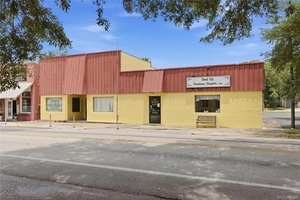 A yellow commercial building with a red metal awning sits along a paved street — 8307 E ORANGE AVENUE, FLORAL CITY, FL