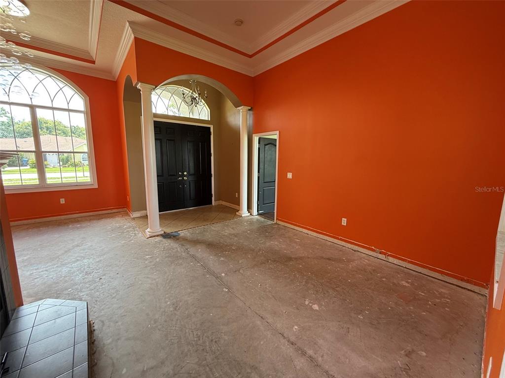 An empty room with orange walls, a concrete floor, and a double-door entryway with columns — 4045 HANGING MOSS LOOP, SPRING HILL, FL