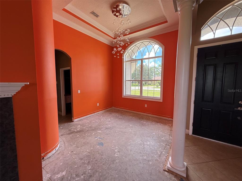 An empty room with bright orange walls, a large arched window, and a modern chandelier — 4045 HANGING MOSS LOOP, SPRING HILL, FL