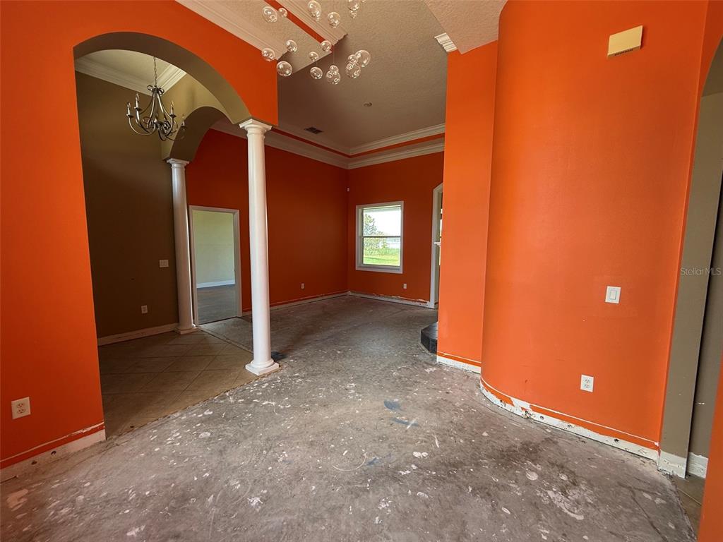 An empty room with bright orange walls, white columns, and unfinished concrete flooring — 4045 HANGING MOSS LOOP, SPRING HILL, FL