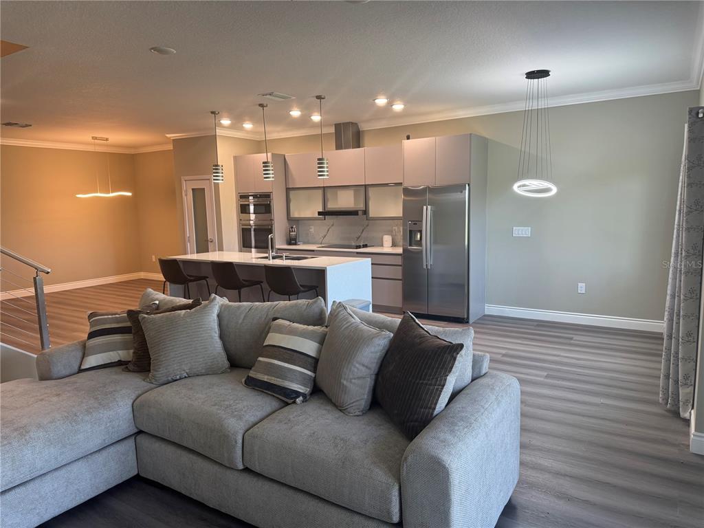 A modern open-concept kitchen features a central island, stainless steel appliances, and gray cabinetry — 2037 GREENBRIAR TERRACE, DAVENPORT, FL