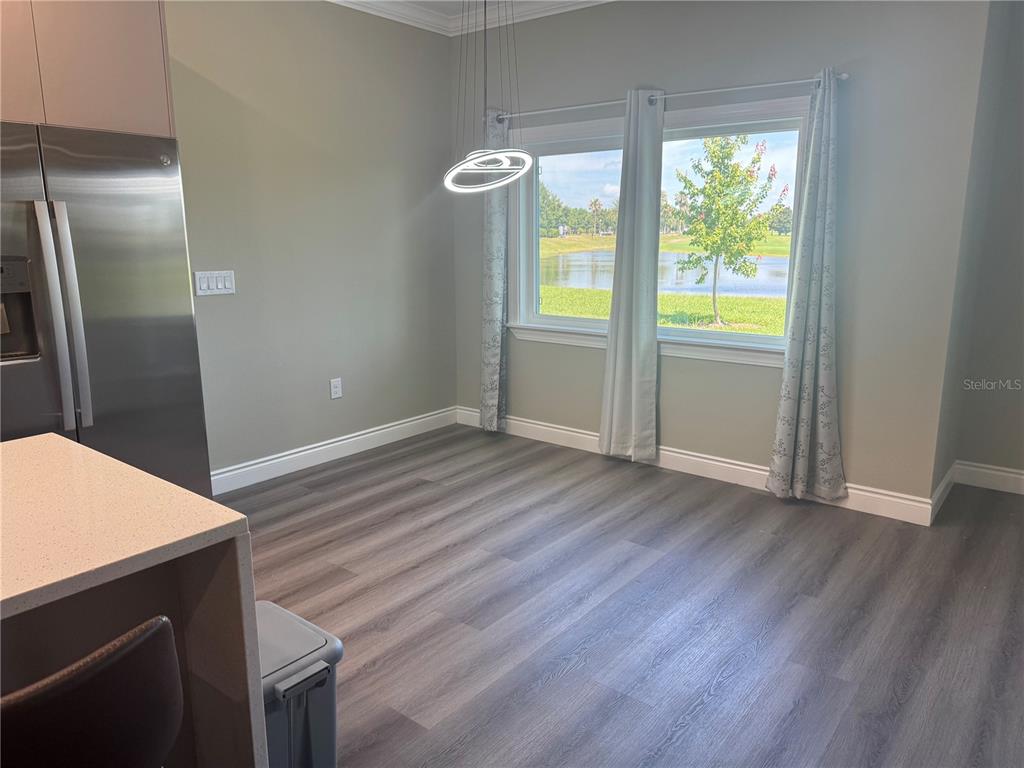 An empty dining area features wood-look flooring, a modern pendant light, and a lake view — 2037 GREENBRIAR TERRACE, DAVENPORT, FL