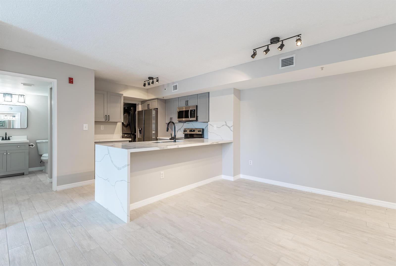 A kitchen with gray cabinets, a marble-patterned island, and light wood-look flooring — 2600 S University Drive # 208, Davie FL 33328, DAVIE, FL