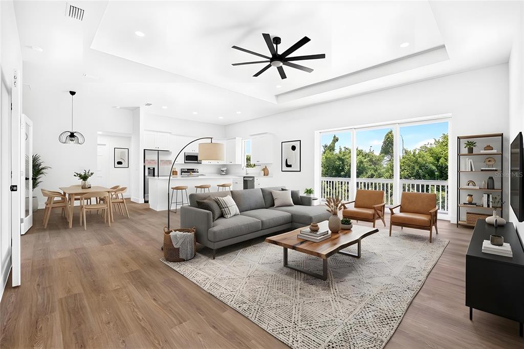 A bright, open-concept living and dining area features white walls, wood flooring, and a tray ceiling — 641 BONITA COURT, PUNTA GORDA, FL