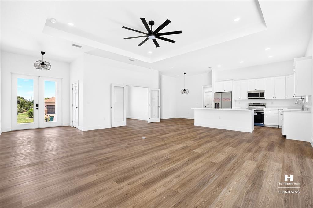 An open-concept living area features white walls, wood-look flooring, a tray ceiling, and a kitchen — 641 BONITA COURT, PUNTA GORDA, FL