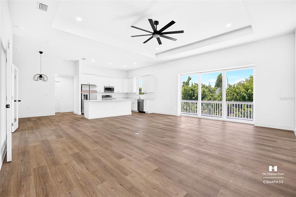 An open-concept living area with a kitchen, wood-look flooring, and a sliding glass door — 641 BONITA COURT, PUNTA GORDA, FL