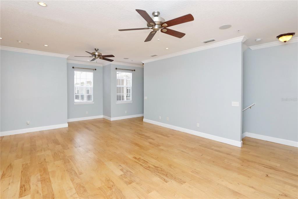 An empty room features light blue walls, hardwood floors, and two ceiling fans — 2611 ESPANA COURT, TAMPA, FL