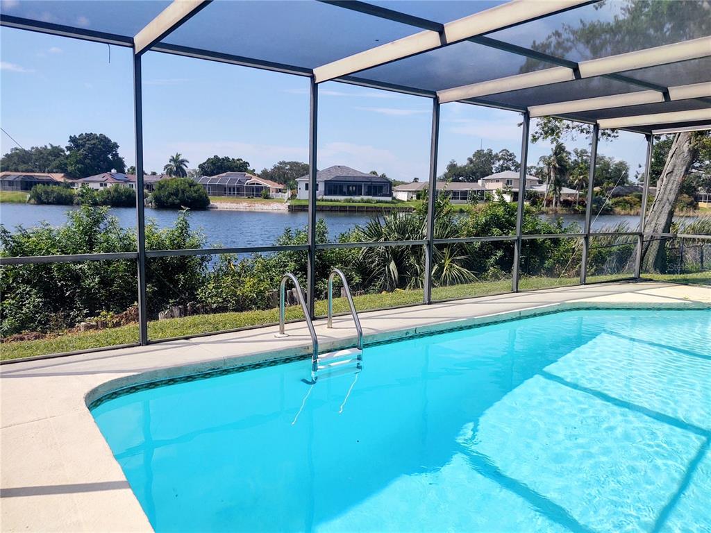 A screened-in swimming pool overlooks a lake and neighboring houses — 619 RIVIERA BAY DRIVE NE, ST PETERSBURG, FL