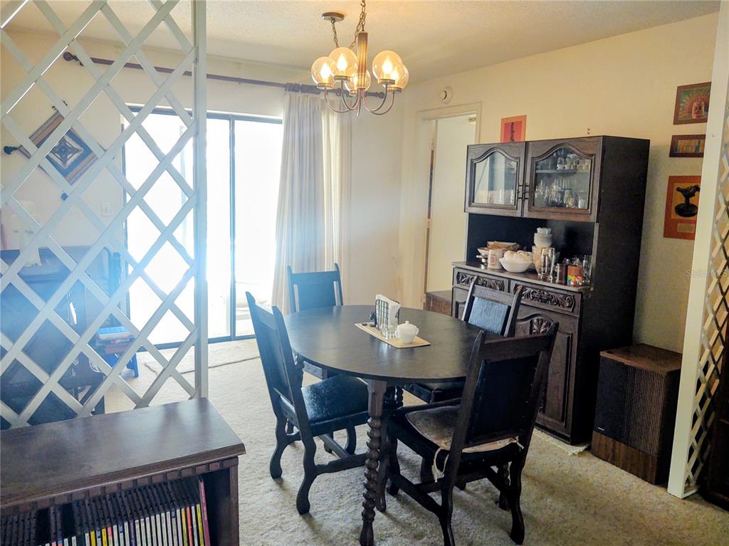 A dining room with a dark wood table, chairs, and a matching hutch on carpet — 619 RIVIERA BAY DRIVE NE, ST PETERSBURG, FL