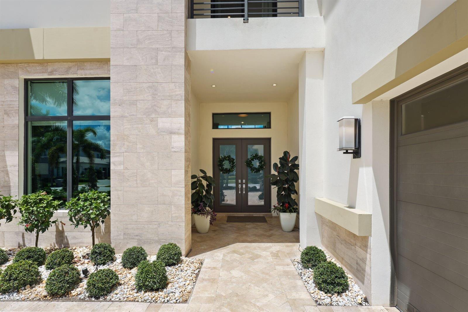The exterior entrance features a stone-tiled walkway, double glass doors, and manicured landscaping — 9275 Biaggio Road, Boca Raton FL 33496, BOCA RATON, FL