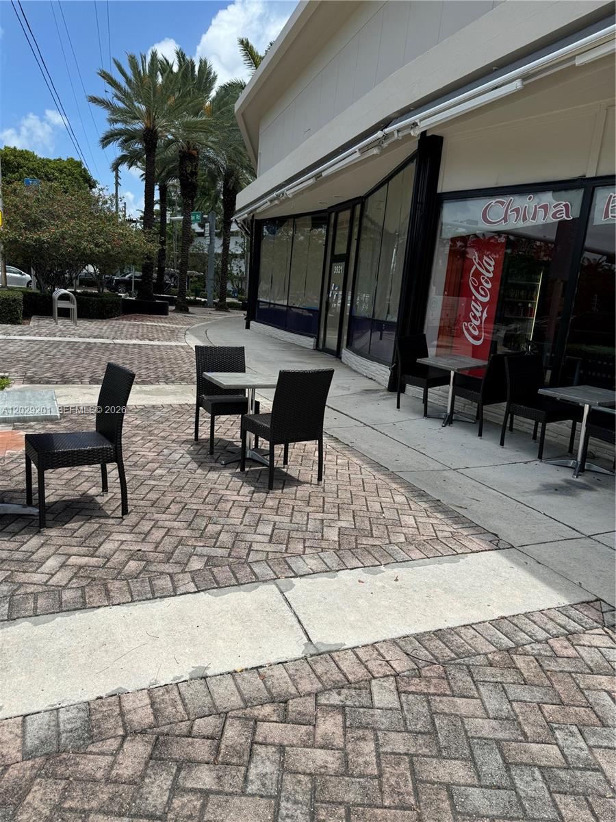 An outdoor patio area features brick pavers, black wicker chairs, and small tables outside a restaurant — 3119 Alton Road, Miami Beach FL 33140, MIAMI BEACH, FL