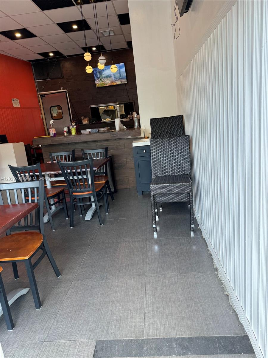 A restaurant interior features dark tile floors, wooden tables, black chairs, and a service counter — 3119 Alton Road, Miami Beach FL 33140, MIAMI BEACH, FL