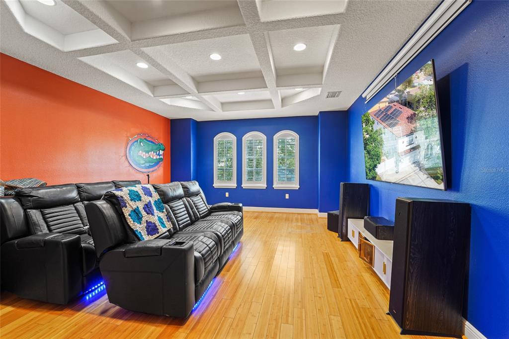 A home theater room features a coffered ceiling, blue and orange walls, and leather seating — 4202 N HOWARD AVENUE, TAMPA, FL