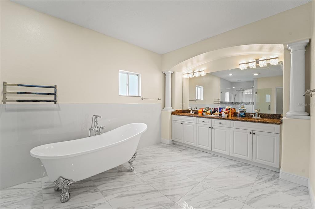 A bathroom features a white clawfoot tub, marble-look tile flooring, and a double vanity — 4202 N HOWARD AVENUE, TAMPA, FL