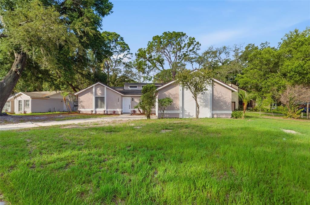 A single-story house with a light-colored stucco exterior and a large front lawn — 108 WESTWIND COURT, SANFORD, FL