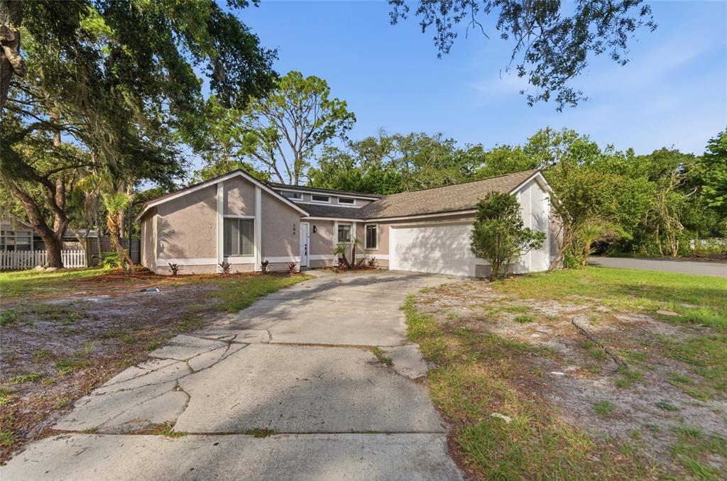 A single-story house with a beige stucco exterior, a cracked concrete driveway, and a garage — 108 WESTWIND COURT, SANFORD, FL