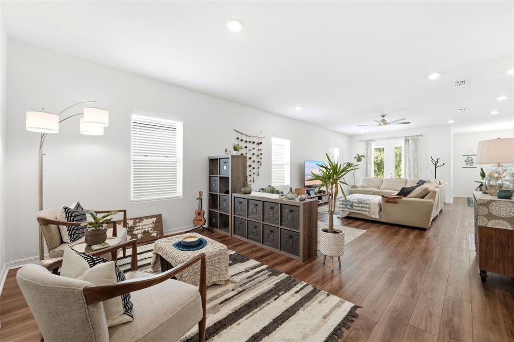 A living room features wood-look flooring, a sectional sofa, two armchairs, and a storage unit — 1525 PLAYWRIGHT DRIVE, DELAND, FL