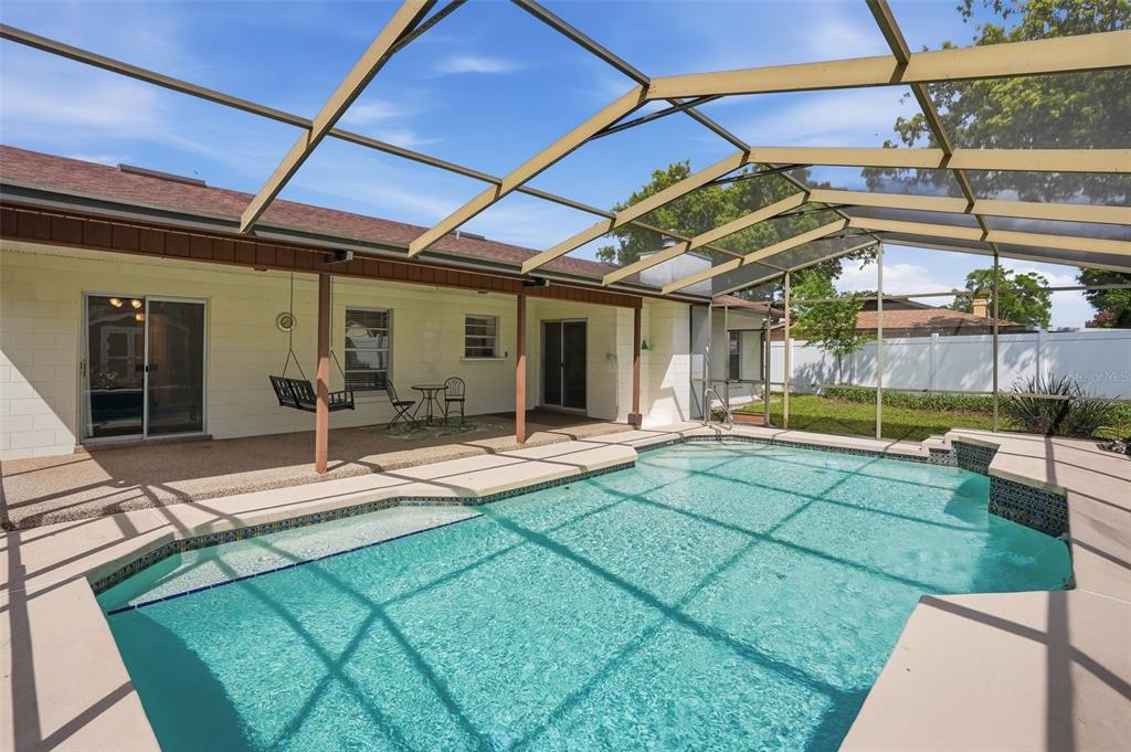 A screened-in patio features a swimming pool and a covered seating area with a swing — 8040 TOWNE COURT, ORLANDO, FL