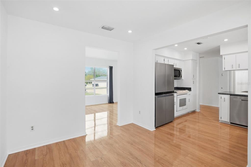 A bright kitchen and dining area with white walls, stainless steel appliances, and wood flooring — 8040 TOWNE COURT, ORLANDO, FL