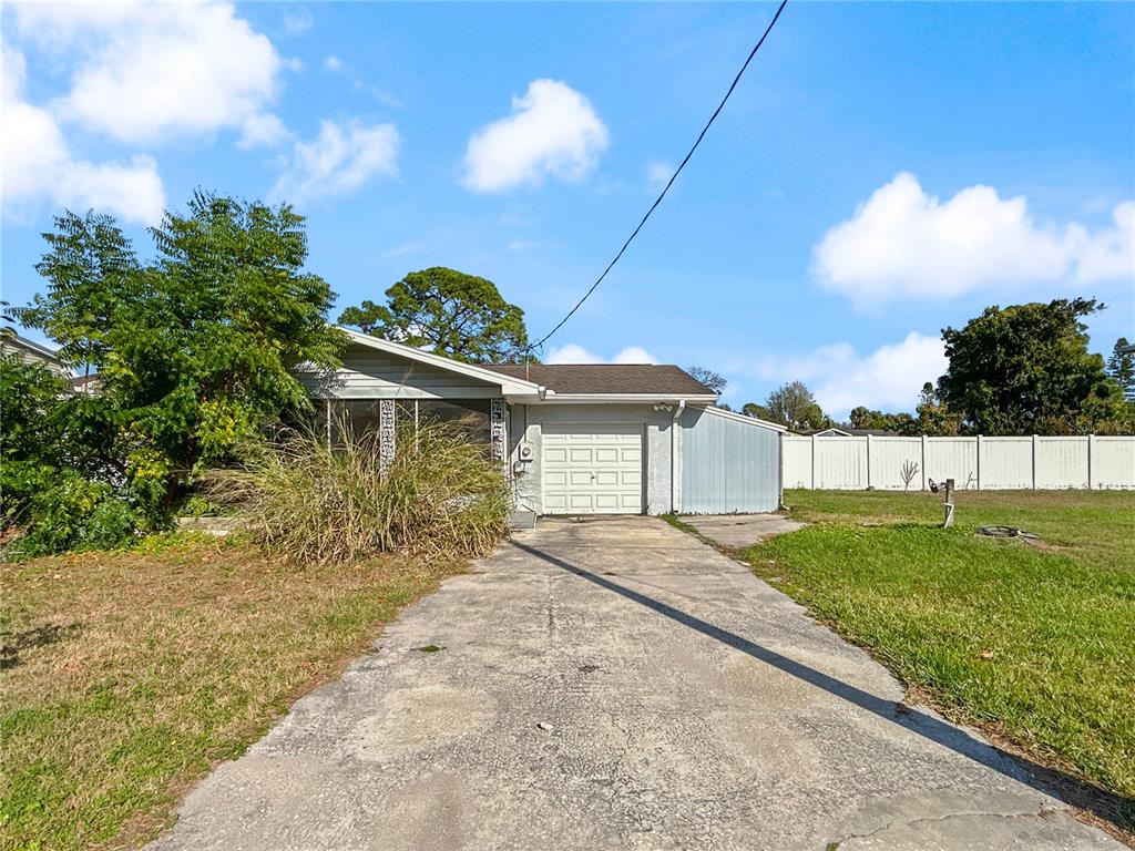 A grassy yard sits between a house with large windows and a canal with boat lifts — 133 NW 18TH STREET, RUSKIN, FL