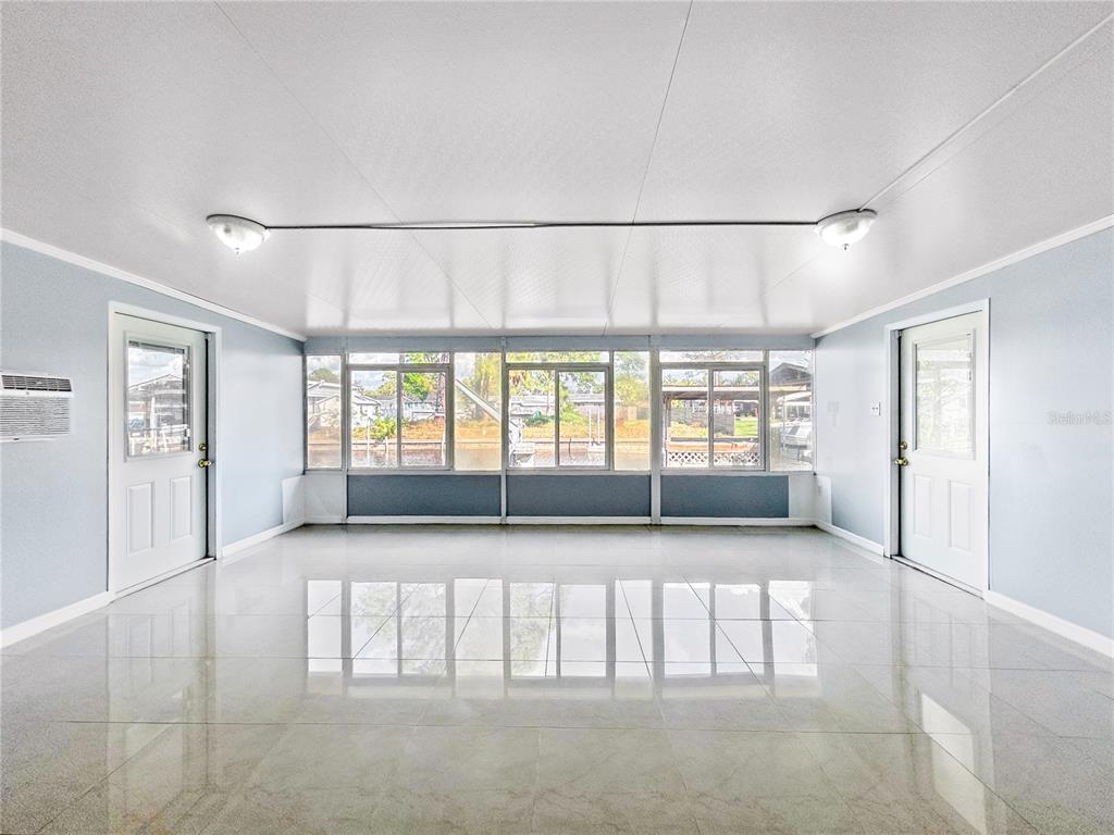 A bright sunroom features white tile flooring, large windows, and a utility area — 133 NW 18TH STREET, RUSKIN, FL