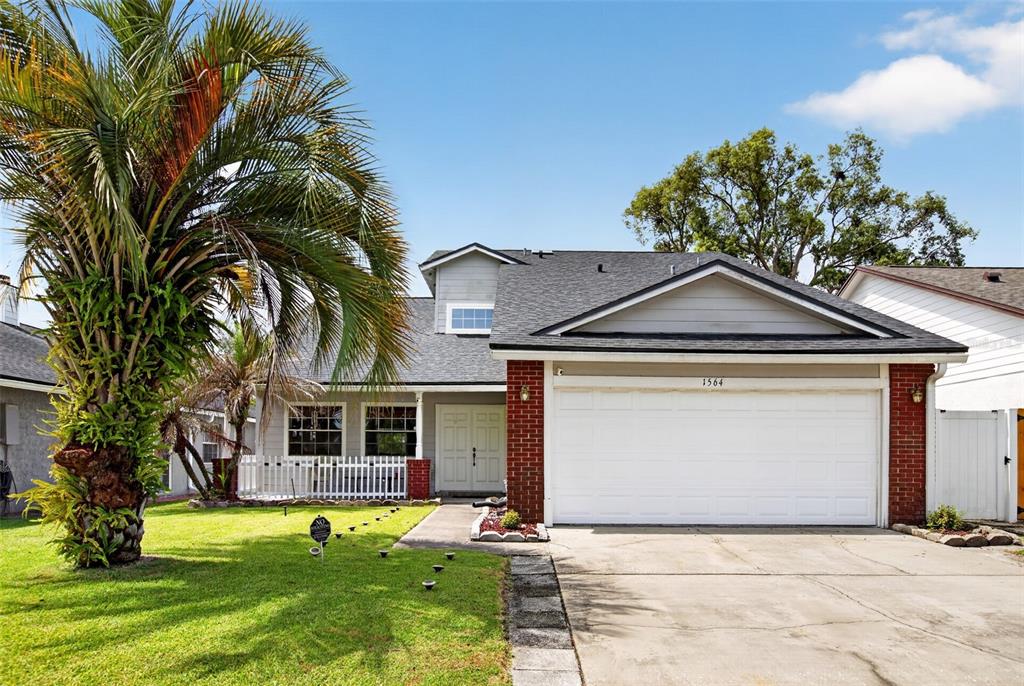 A two-story house with a brick facade, a white garage door, and a palm tree — 1564 LAWNDALE CIRCLE, WINTER PARK, FL