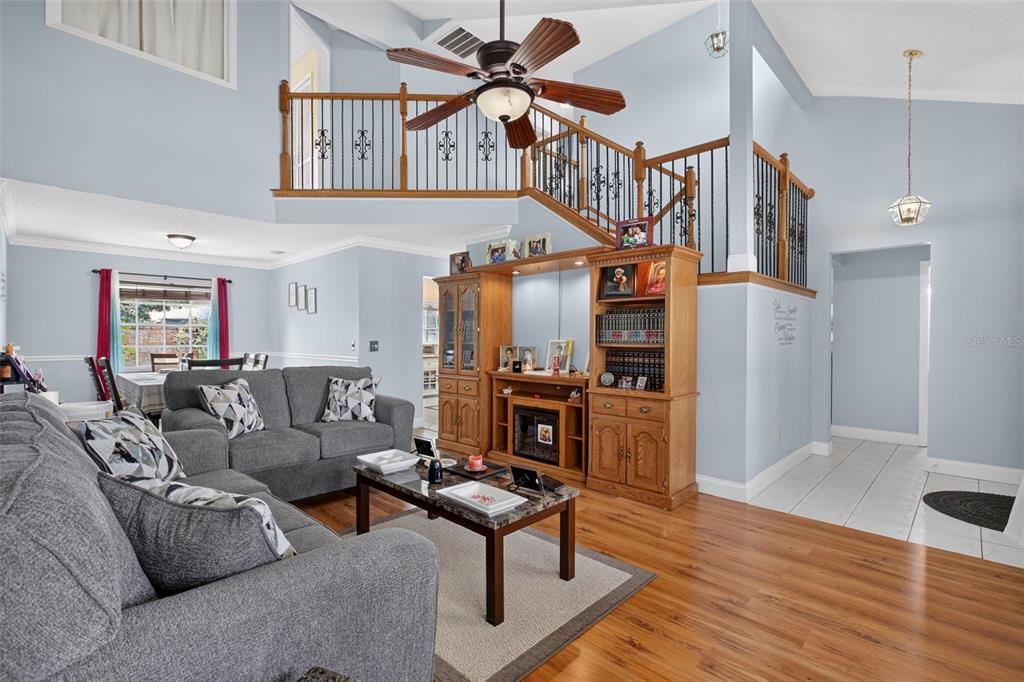 A living room with light blue walls, wood flooring, a fireplace unit, and a lofted balcony — 1564 LAWNDALE CIRCLE, WINTER PARK, FL